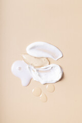 Drops and smears of cosmetics top view on beige background