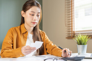 Asian young employee, business woman calculate tax income and expenses, bills, credit card for...