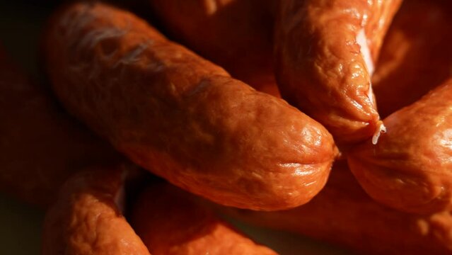 Close-up view 4k stock video footage of organic smoked sausages isolated on green plate background