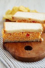 Homemade Pimento Cheese Sandwich with Chips on a rustic wooden board, side view. Close-up.