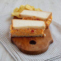 Homemade Pimento Cheese Sandwich with Chips on a rustic wooden board, side view.