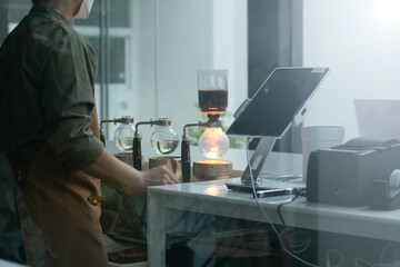 Coffee shop worker standing at the counter with hand drip coffee set