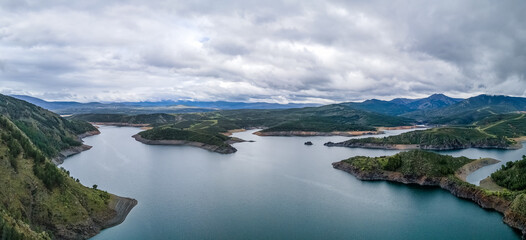 Landscape of a lake between the green mountains on a cloudy day, aerial view.
