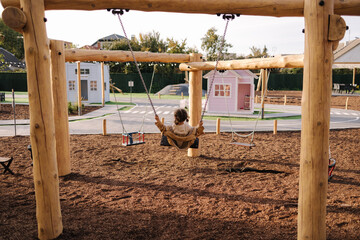 Back view of cute little girl swing on a swing in the specially designated place in the park....