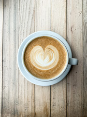 A cup of coffee latte On a wooden table. A mug of flat white coffee on a wooden background. Coffee art. Heart flower shape latte art. Copy space