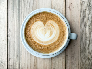 A cup of coffee latte On a wooden table. A mug of flat white coffee on a wooden background. Coffee art. Heart flower shape latte art. Copy space
