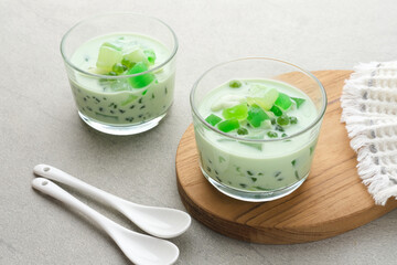 Buko Pandan, a dessert from Philippines, made from jelly, young coconut, evaporated milk, sweetened condensed milk, and ice. Served on glass with cheese topping. Selective focus.
