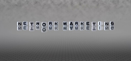 network marketing word or concept represented by black and white letter cubes on a grey horizon background stretching to infinity