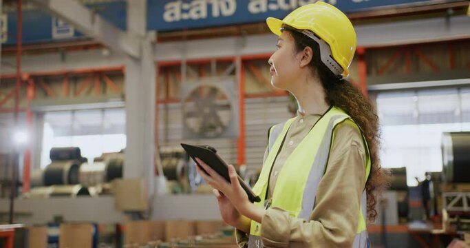Asian worker standing in industrial construction site and using digital tablet