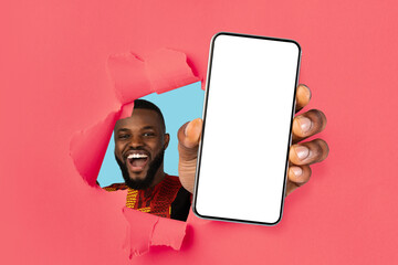Excited guy showing white empty smartphone screen through torn paper