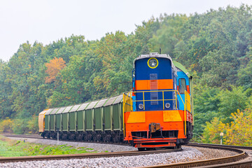 Obraz premium The locomotive pulls wagons loaded with grain from the elevator to the railway station. Summer evening lighting. Close-up view.