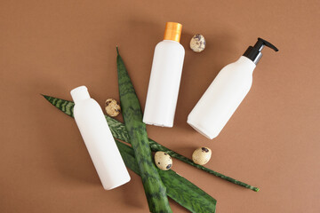 three different mockup bottles for cosmetics and quail eggs on a brown background