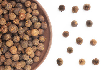 Spice Allspice in clay plate and bunch on white background. Flat lay. Brown color. Indian cuisine concept