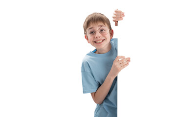 Joyful cheerful boy peeks out from behind whiteboard with an empty space for your text or...