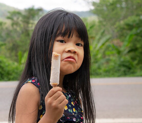 Portrait of  adorable little Asian girl with long black hair dress casual holding ice cream. Happy and holiday concept.