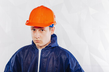 Male construction engineer on a white background in an orange helmet and blue overalls