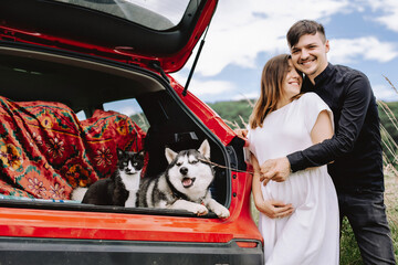 Travel concept with pets. A happy family is expecting a baby and resting with a cat and dog in...