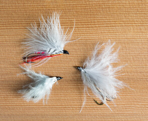 Three hand tied fluffy fly fishing flies on a wood background.