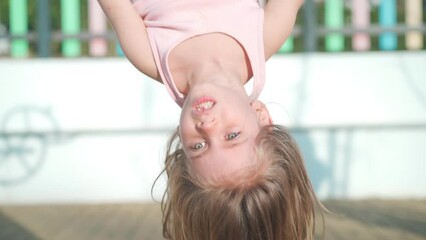 Child playing on playground warm summer day. Little girl have fun. Happy childhood. Caucasian little girl 5 years play outdoor hanging upside down