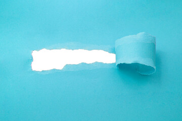 Hole in paper blue color background damaged ripped