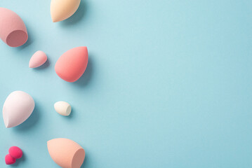 Makeup concept. Top view photo of different colour beauty blenders on isolated pastel blue background with copyspace