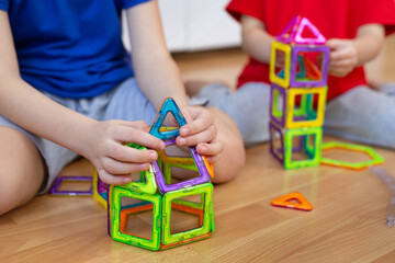 Brother and sister are playing with a magnetic construction toy. Close-up details