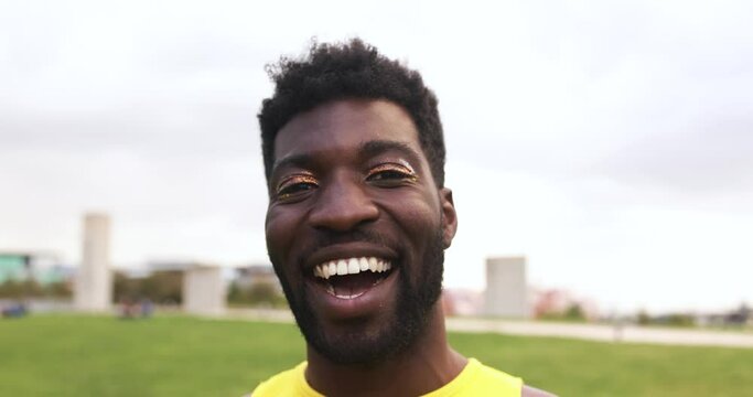 Young african man with make up smiling on camera at city park
