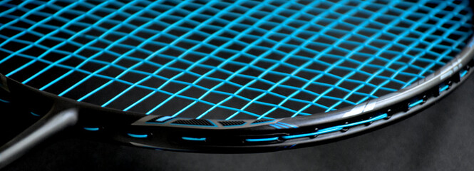 Cream white badminton shuttlecock and racket with neon light shading on dark floor in indoor badminton court, copy space, soft and selective focus.