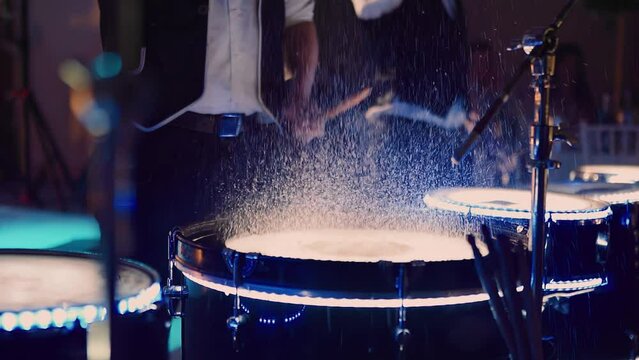 The drummer strikes the drums doused with water. The spray flies beautifully to the sides. The drums are also illuminated by diode illumination