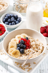 homemade oatmeal with berries for breakfast, vertical closeup