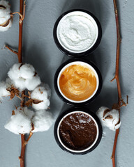 Body cream of different colors. Set with different body scrubs on gray mist, top view. Banner design