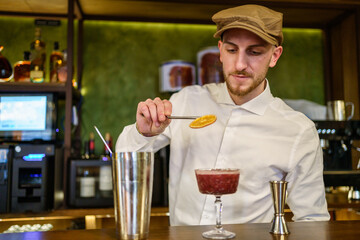 Bearded mixologist garnishing exquisite cold cocktail