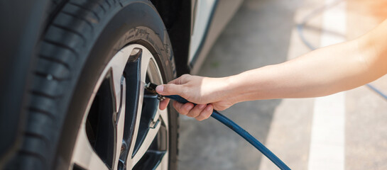 hand inflating tires of vehicle, checking air pressure and filling air on car wheel at gas station....