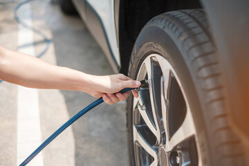 hand inflating tires of vehicle, checking air pressure and filling air on car wheel at gas station....