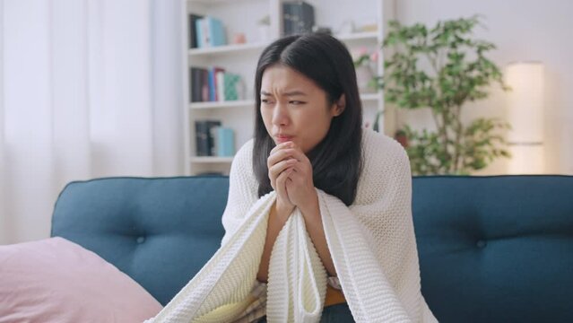 Woman trying to warm up cold hands, law temperature at home, expensive heating