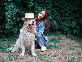 Portrait of yound happy woman playing with golden retriever labrador dog and straw hat