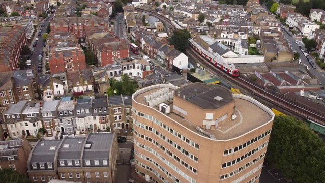 A drone view of a skytrain crossing Putney Bridge Rd in London.