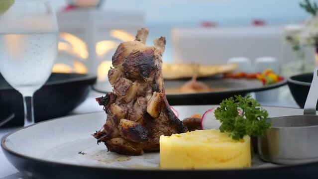 Hot grilled rack of lamb with mashed potato and onions on dinner or lunch. White plate with roasted lamb ribs chops and vegetables garnish on table in luxury restaurant. Delicious food concept.