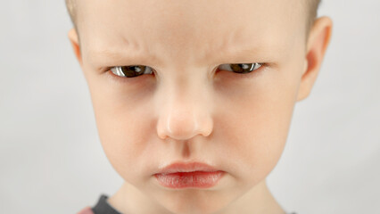 Portrait caucasian boy 4 years old, angry child expresses emotions of discontent or anger looks at...