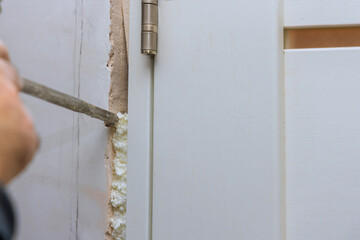 Technology on construction foam between the wall and the door frame a home under reconstruction - obrazy, fototapety, plakaty