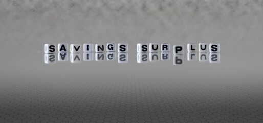 savings surplus word or concept represented by black and white letter cubes on a grey horizon background stretching to infinity
