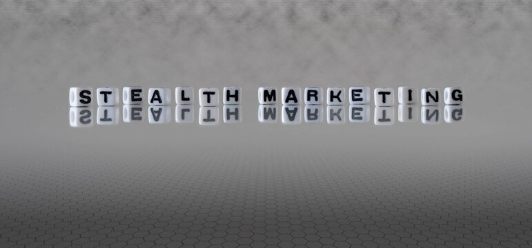 stealth marketing word or concept represented by black and white letter cubes on a grey horizon background stretching to infinity
