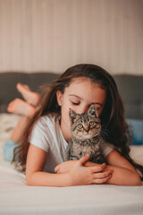  little girl lying in bed and hug the kitten 