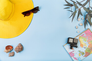 Summer vacation layout, on a blue background map of the world, shells, camera and yellow hat, copyspace