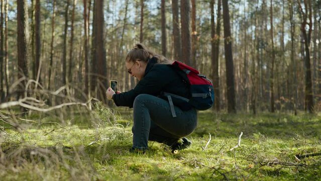 girl takes a picture of a guy on the phone in the forest