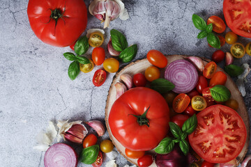 Flat lay composition of different tomatoes, onion, basil and garlic