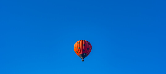 Red hot air balloon decorated as ladybird flying in clear blue sky. copy space