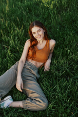 A young happy woman lying relaxed on the grass in the park, the lifestyle of a happy person without depression