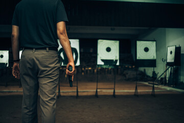 Professionals carry a 9mm pistol inside a shooting range. - obrazy, fototapety, plakaty