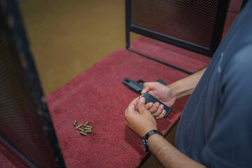 A profesional holds a 9mm pistol and is reloading in a safe stance inside a shooting range.